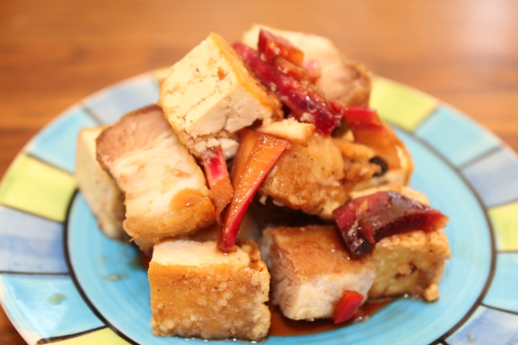 A colorful plate of Tokwa't Baboy, featuring cubes of crispy pork and tofu, garnished with sliced red and green peppers, served on a blue plate.